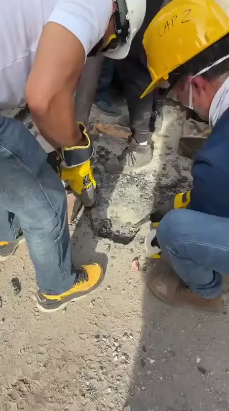 Personas con cascos trabajan con herramientas entre materiales de construcción.