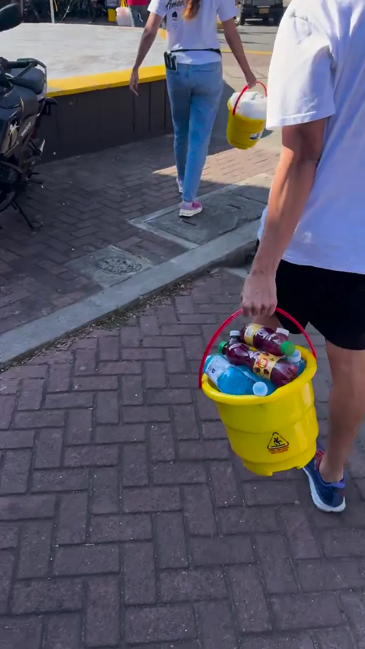Personas trasladan baldes con artículos por un andén.