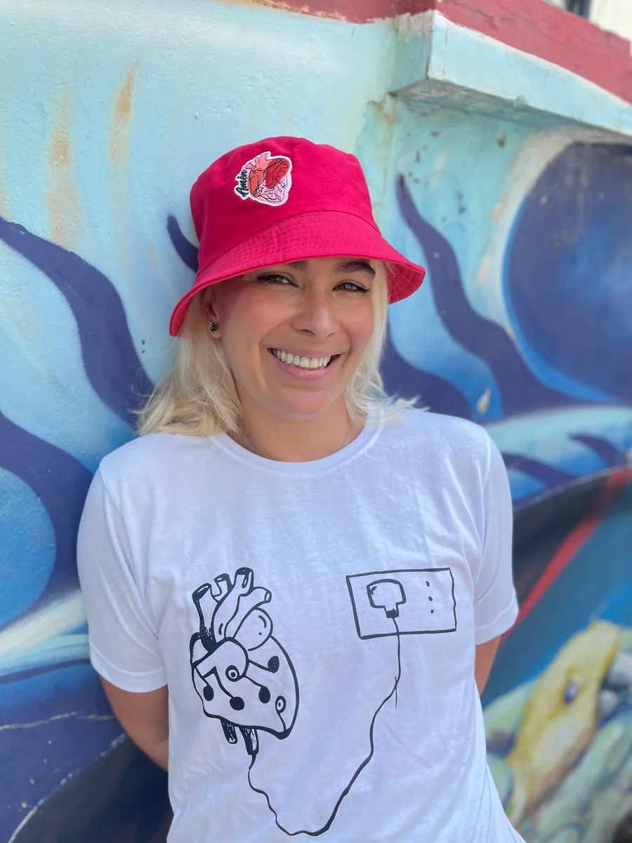 Camiseta con un corazón dibujado y sombrero rojo con el logo de AMEN.