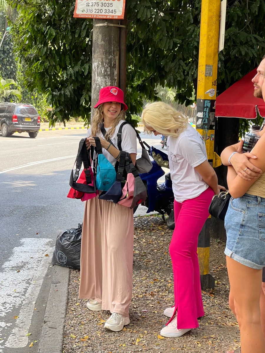 Personas con camisetas de AMEN y canguros de varios colores en una acera.