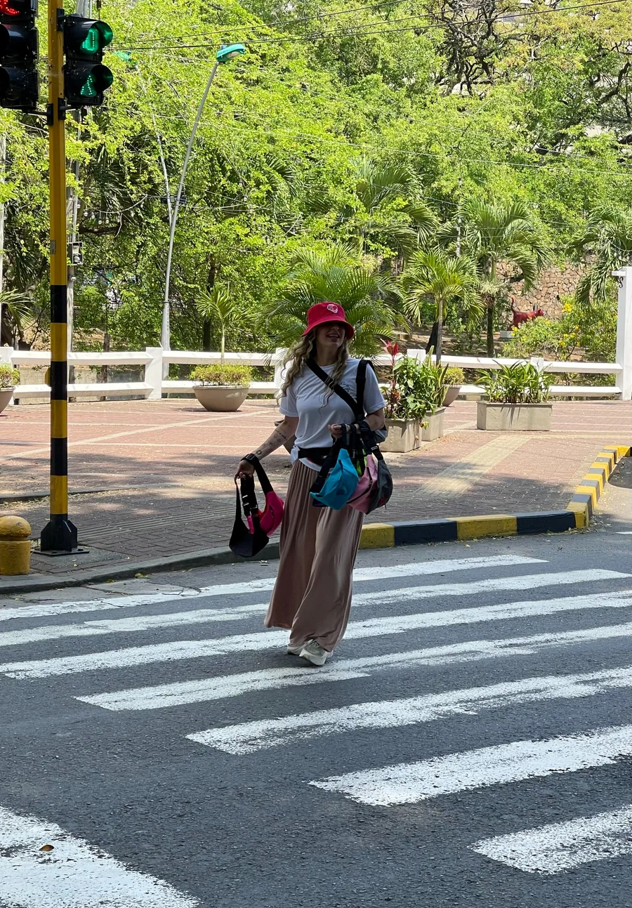 Una persona con sombrero rojo y canguros cruza por un paso peatonal.